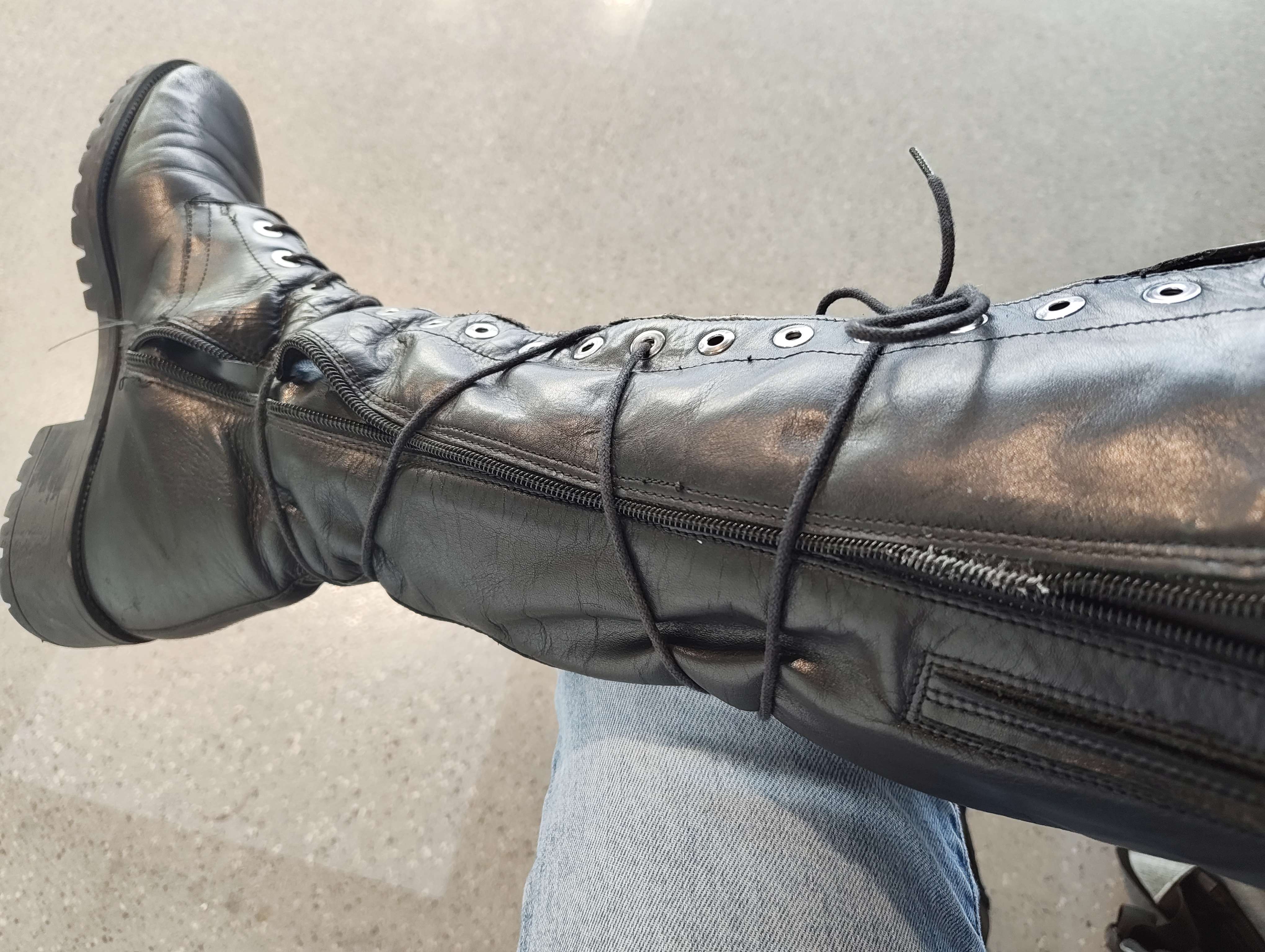 A photo of a black, knee-high boot. The laces have been wrapped around the whole thing several times in a criss-cross pattern, and tied in a knot near the top.