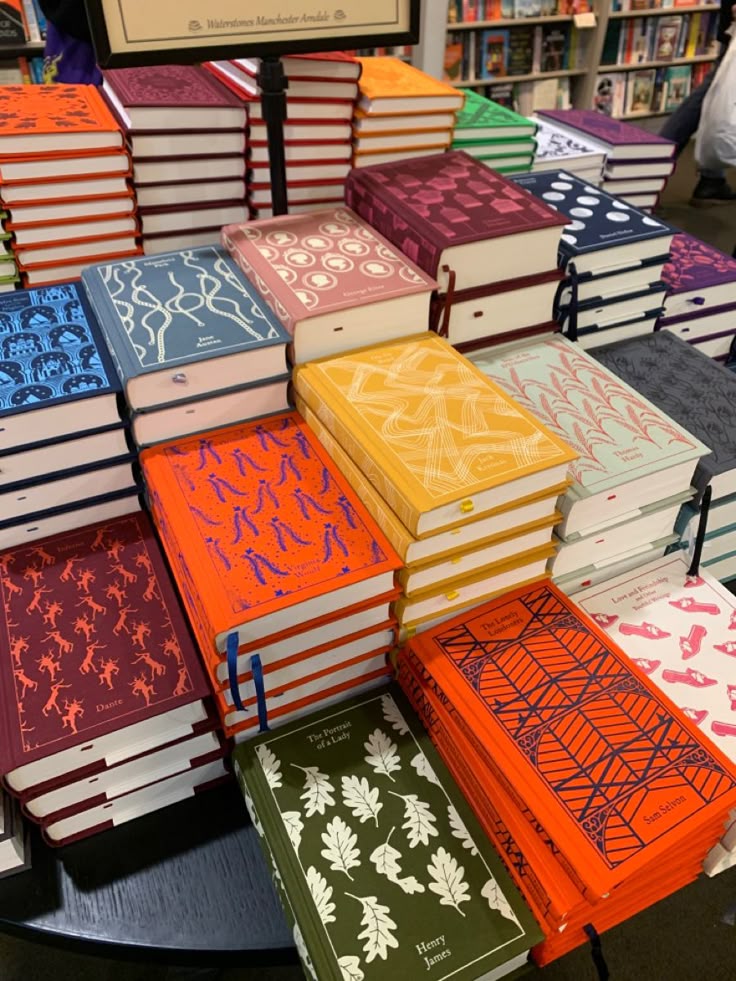 A neat pile of various Clothbound Classic books. Classic Western novels with single-colour covers, with a minimalist pattern, representing something from the book, in a different cover.